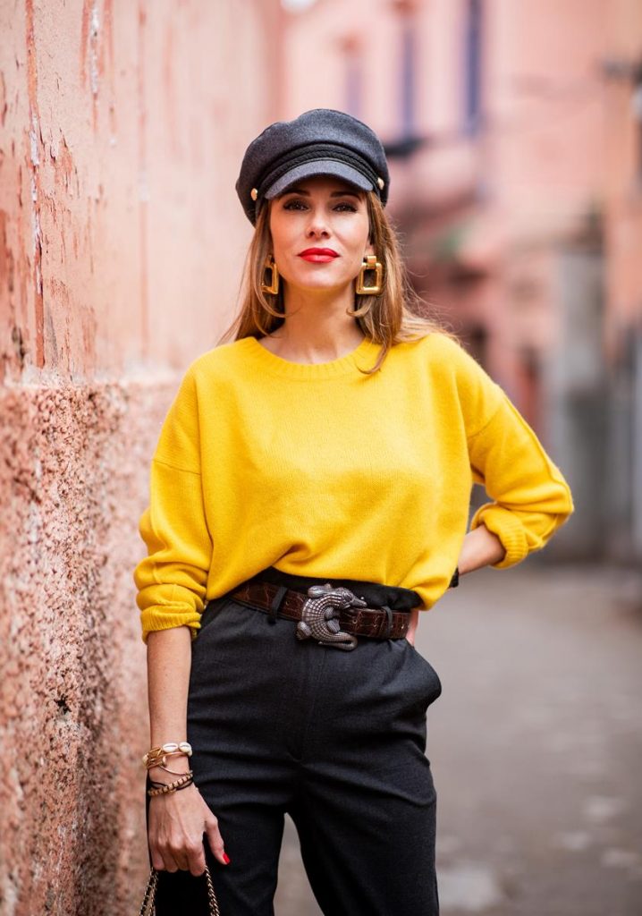 Alexandra Lapp in a Yellow Knit look, wearing a yellow crew-neck cashmere sweater from Jardin des Orangers, high-waisted trousers in dark grey by H&M, Graphic Flap Bag from Chanel in black/red/yellow/blue, brown lacquer Kieselstein Cord Crocodile belt, red lacquer pumps from Gianvito Rossi and dark grey nautical cap with buttons by ZARA on November 25, 2018 in Marrakech, Morocco.