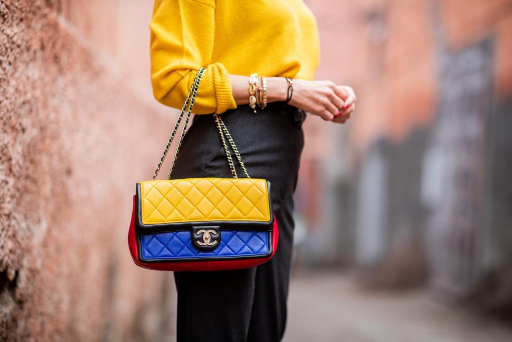 Alexandra Lapp in a Yellow Knit look, wearing a yellow crew-neck cashmere sweater from Jardin des Orangers, high-waisted trousers in dark grey by H&M, Graphic Flap Bag from Chanel in black/red/yellow/blue, brown lacquer Kieselstein Cord Crocodile belt, red lacquer pumps from Gianvito Rossi and dark grey nautical cap with buttons by ZARA on November 25, 2018 in Marrakech, Morocco.