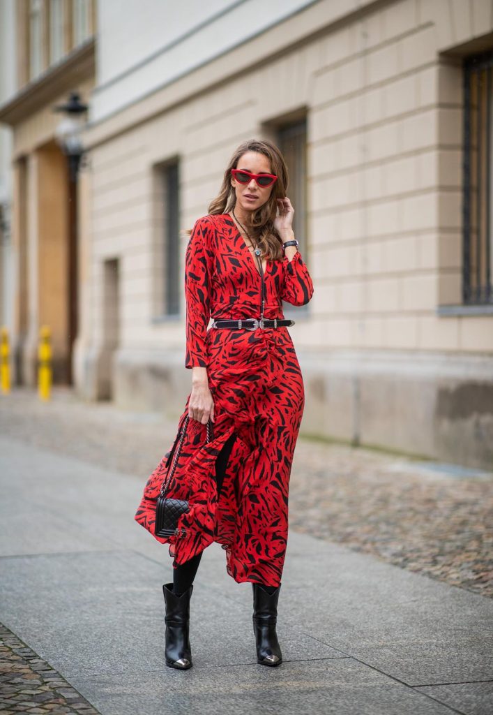 Alexandra Lapp in a Red Animal Print Look, wearing the long Adriana animal print dress from Rixo, a black and white wool coat from Ganni, the Isabel Marant Lamsy cowboy boots, a black boy bag from Chanel, a silver buckled H&M cowboy belt, a western cowboy necklace and red cat-eyed sunglasses by Celine during the Berlin Fashion Week Autumn/Winter 2019 on January 15, 2019 in Berlin, Germany. (Photo by Christian Vierig/Getty Images)