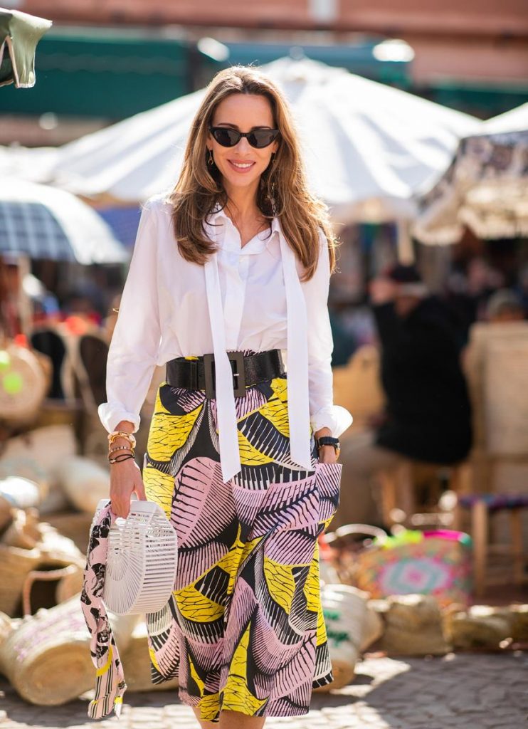 Alexandra Lapp in a Le Riad look, wearing a flared skirt printed with pink, yellow and black patterns combined with a plain bowed white shirt, a matching silk printed scarf with elephants in the same colours and round big earrings in black all by Marc Cain, leather sandals in white, white bag and black cat-eyed shaped sunglasses on November 25, 2018 in Marrakech, Morocco. (Photo by Christian Vierig/Getty Images)