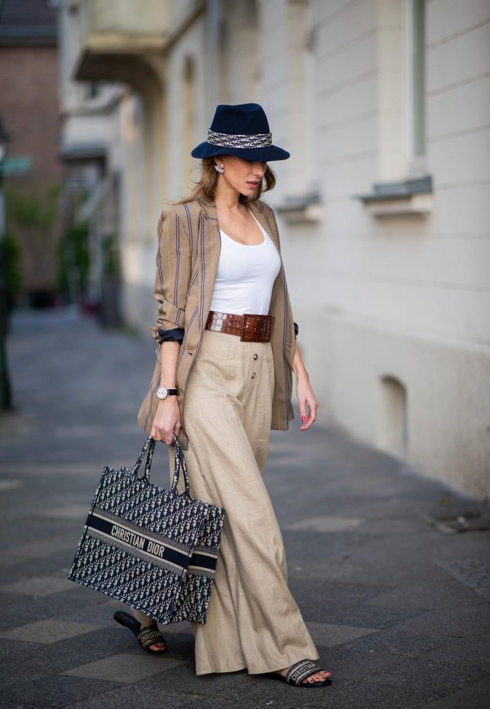 Alexandra Lapp in a Dior Book Tote Bag Look, wearing a beige brown long striped blazer from Zara, white tank top from H&M, waisted belt from Max Mara, high waisted wide leg pants from Staud, Dior Dway mules, Dior Book Tote Dior Oblique bag and a Dior foulard on a blue Borsalino hat on May 04, 2019 in Duesseldorf, Germany. (Photo by Christian Vierig/Getty Images)
