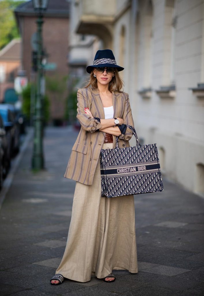 Alexandra Lapp in a Dior Book Tote Bag Look, wearing a beige brown long striped blazer from Zara, white tank top from H&M, waisted belt from Max Mara, high waisted wide leg pants from Staud, Dior Dway mules, Dior Book Tote Dior Oblique bag and a Dior foulard on a blue Borsalino hat on May 04, 2019 in Duesseldorf, Germany. (Photo by Christian Vierig/Getty Images)