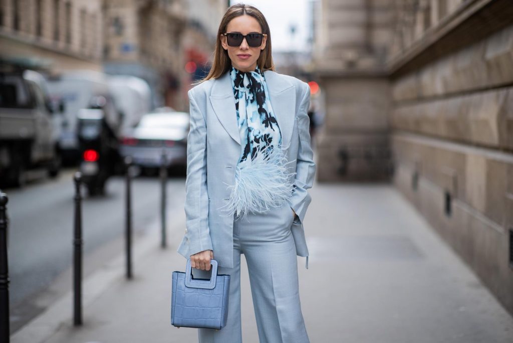 PARIS, FRANCE - FEBRUARY 25: Alexandra Lapp is seen wearing a suit style, light blue De La Vali suit, blue Shirley mini bag from Staud, 16Arlington satin top with feathers, Prada pumps in light blue, square-frame black Bottega Veneta sunglasses all from Net-A-Porter during Paris Fashion Week - Womenswear Fall/Winter 2020/2021 : Day Two on February 25, 2020 in Paris, France.