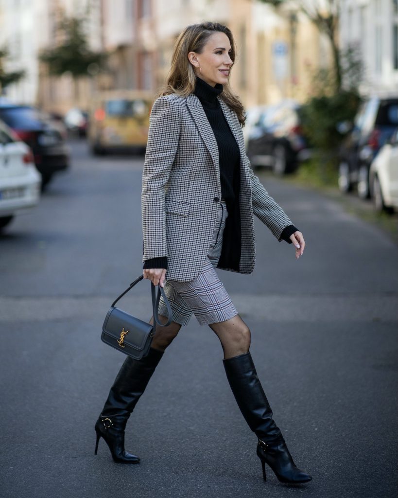 Alexandra Lapp is seen wearing a grey Saint Laurent checked blazer, black turtleneck pullover, glen check ¾ trousers, cross body bag, Celine sunglasses, Jimmy Choo boots