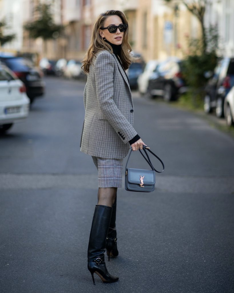 Alexandra Lapp is seen wearing a grey Saint Laurent checked blazer, black turtleneck pullover, glen check ¾ trousers, cross body bag, Celine sunglasses, Jimmy Choo boots