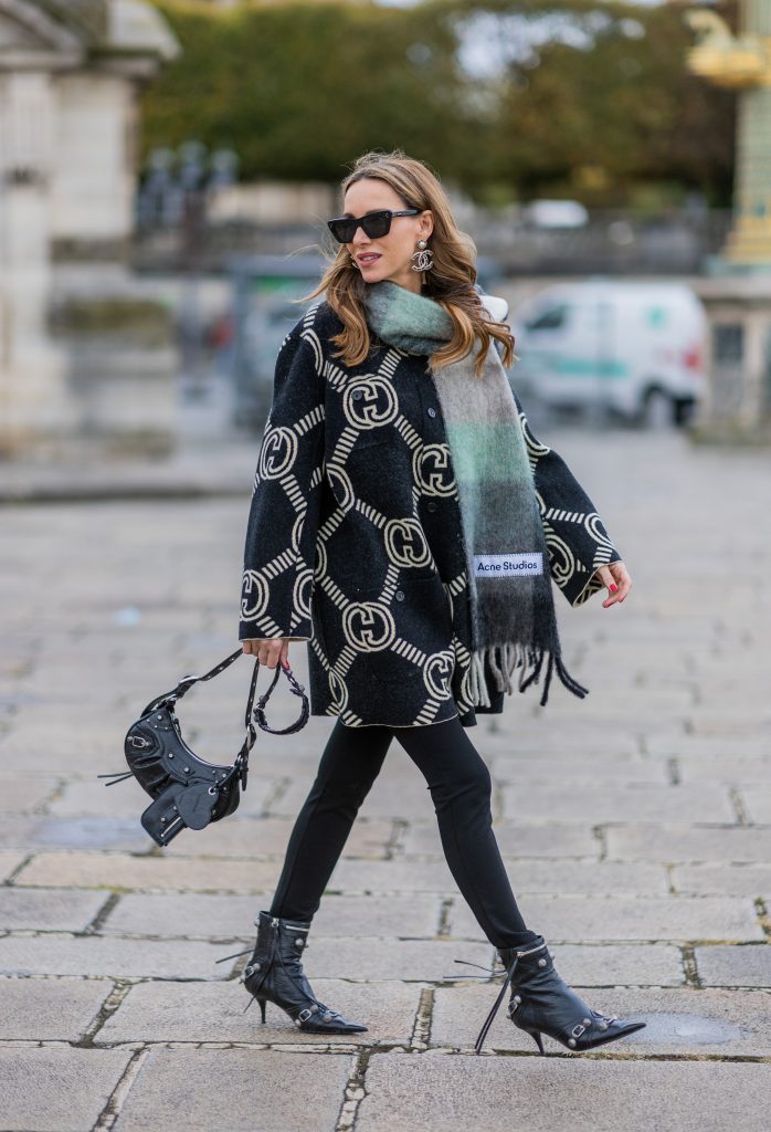 Alexandra Lapp is seen wearing GUCCI reversible cardigan in black and ecru, BALMAIN pants in black, ACNE STUDIOS scarf in green and grey, BALENCIAGA Le Cagole bag in black, BALENCIAGA ankle boots Cagole in black, CELINE cat eye sunglasses in silver, and Chanel ear rings in black. 