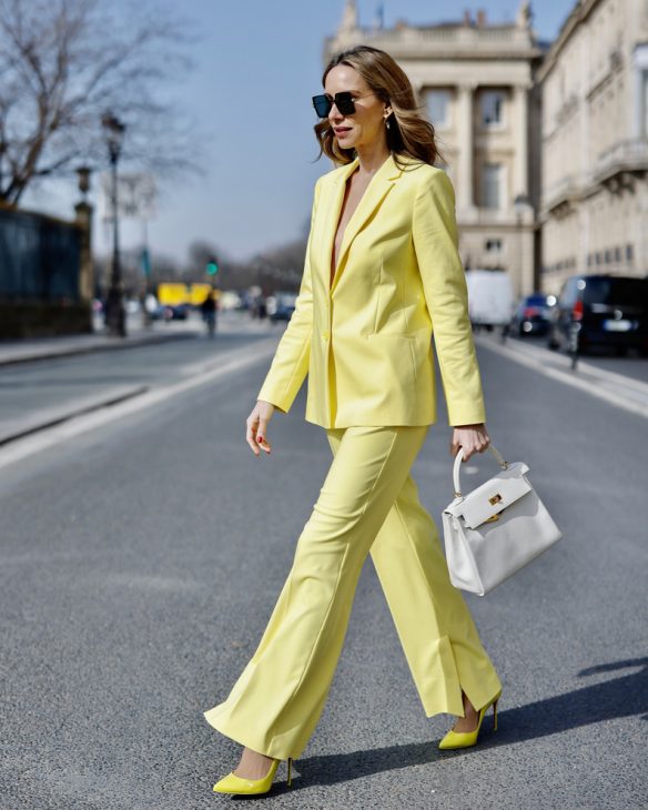 Alexandra Lapp is seen wearing colorful looks during Paris Fashion Week. COMMA blazer and trousers in yellow, Chanel flap bag in white, CHRISTIAN LOUBOUTIN Hot Chick pumps in yellow, and FOR ART’S SAKE sunglasses in brown.