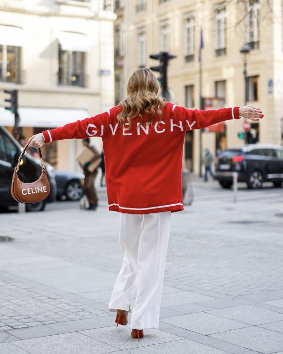 Alexandra Lapp is seen wearing colorful looks during Paris Fashion week by GIVENCHY cut-out shoulder cardigan in red, JIL SANDER blouse in white, MAX MARA wide legged pants in creme, CELINE belt in cognac, CELINE Ava strap bag in cognac, CELINE sunglasses, and CHRISTIAN LOUBOUTIN So Kate pumps in cognac. Total look via La Boutique Conceptstore, Dresden.