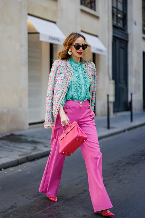 Alexandra Lapp is seen wearing colorful look during Paris Fashion Week by MAISON COMMON tweed jacket in green and pink, MAISON COMMON ruffles blouse in green, MAISON COMMON flared trousers in pink, ZARA heart ear rings in gold, HERMES Kelly bag in pink, and PRADA pumps in pink.